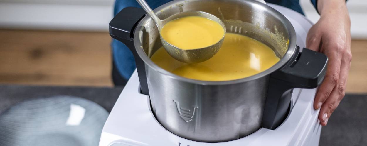 Jemand holt mit einer Kelle Suppe aus dem Monsieur Cuisine