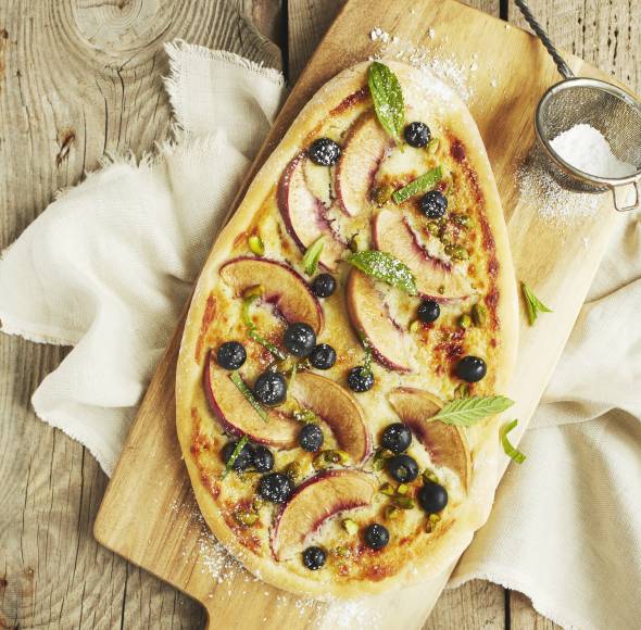 Süße Pizza mit Pfirsichen und Blaubeeren