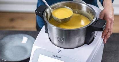 Suppe im Mixtopf, die mit einer Kelle herausgeschöpft wird.