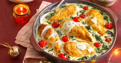 Hähnchenbrustfilet in einer Pfanne mit cremiger Soße mit Spinat und Tomaten