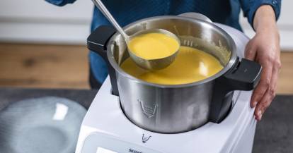 Jemand holt mit einer Kelle Suppe aus dem Monsieur Cuisine