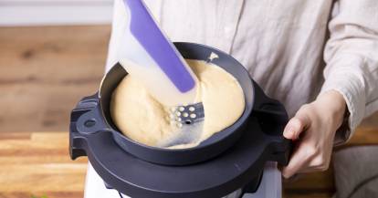 Spätzleteig mit dem Spatel in den Mixbehälter des Monsieur Cuisine schaben