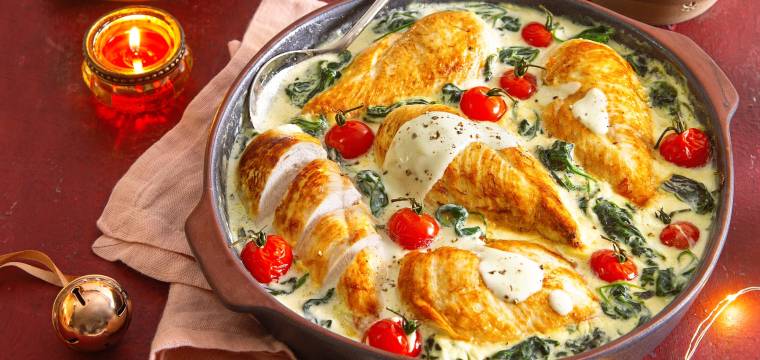 Hähnchenbrustfilet in einer Pfanne mit cremiger Soße mit Spinat und Tomaten